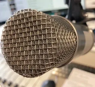Close-up of a condenser microphone positioned in a soundproof recording studio.
